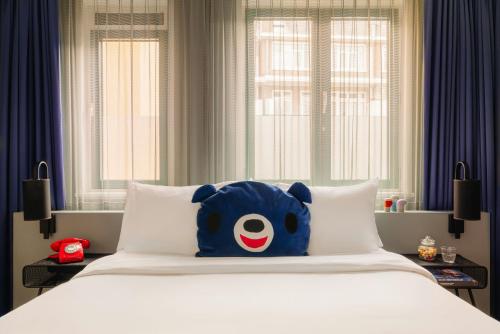 a blue teddy bear sitting on top of a bed at Leonardo Hotel Amsterdam Leidse Square in Amsterdam