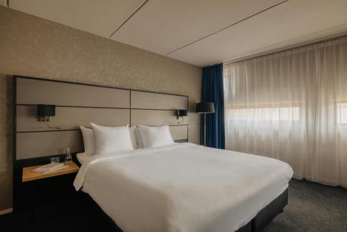 a large white bed in a hotel room at Leonardo Hotel Groningen City Center in Groningen