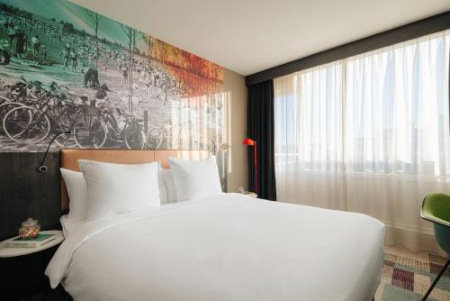 a bedroom with a large white bed and a window at Leonardo Hotel Rotterdam Savoy in Rotterdam