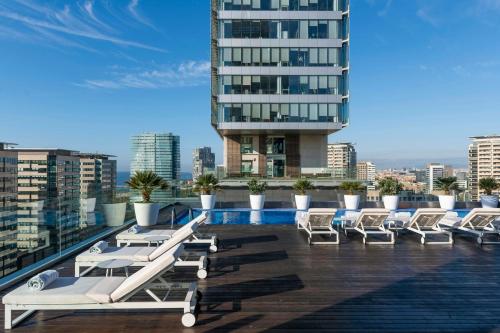 a row of lounge chairs on the roof of a building at Leonardo Royal Hotel Barcelona Forum in Barcelona
