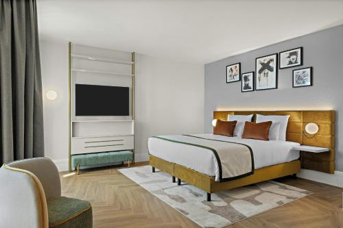 a bedroom with a large bed and a television at Leonardo Hotel Mainz in Mainz