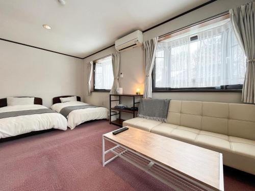 a hotel room with two beds and a couch at ドッグランがある宿-ペンション歩野慕野-honobono in Kitashiobara