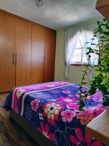 a bedroom with a bed with a flowered blanket at La Casa de Lu cerca de Volcanic park in San Martín Ojo de Agua