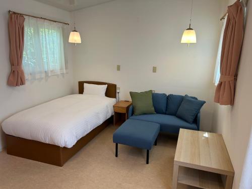 a bedroom with a bed and a blue couch at Hotel El faro in Onagawa