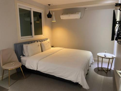 a bedroom with a large white bed and a table at IDEA Hotel in Busan