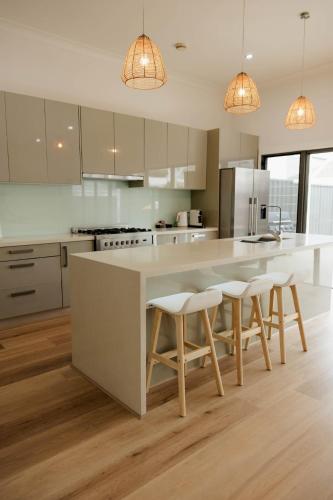 a kitchen with a large white island with bar stools at Vida Hamilton - 3 bed, 2 bath kids playground! in Hamilton