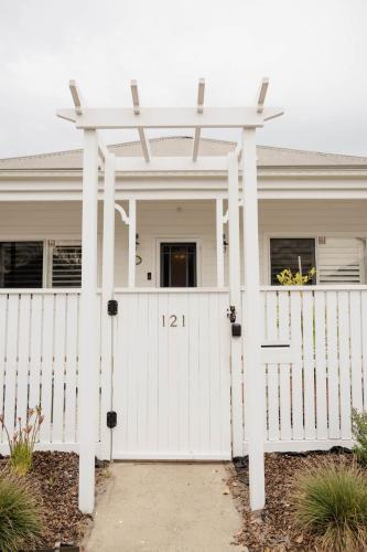 a white house with a gate and a white fence at Vida Hamilton - 3 bed, 2 bath kids playground! in Hamilton