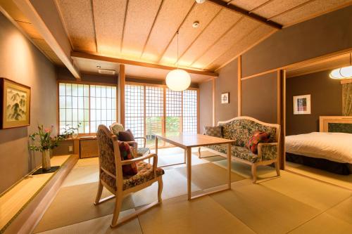 a living room with a table and chairs and a bed at Yufuin Souan Kosumosu in Yufu