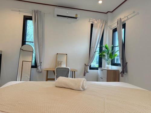 a bedroom with a bed and a chair and windows at Very Central Boho Home in Srithanu in Ko Kong Nui