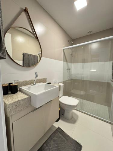 a bathroom with a sink and a toilet and a mirror at Edifício Catamara in Vila Velha