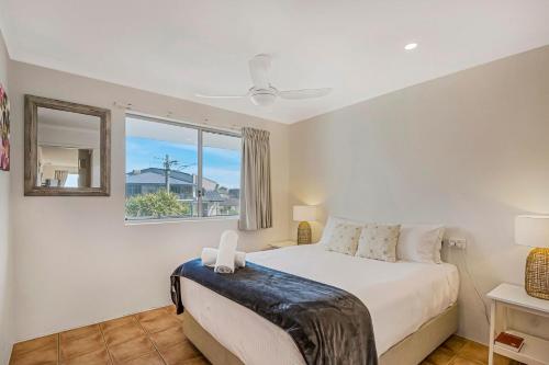 a white bedroom with a bed and a window at 10T Beachfront Apartments in Lennox Head