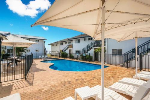 a swimming pool with umbrellas and chairs and a pool at 10T Beachfront Apartments in Lennox Head