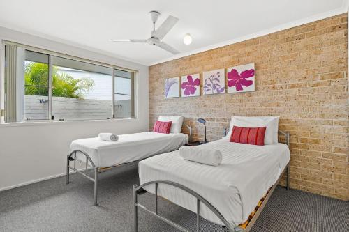 two beds in a room with a brick wall at Ballina Golf Unit in East Ballina