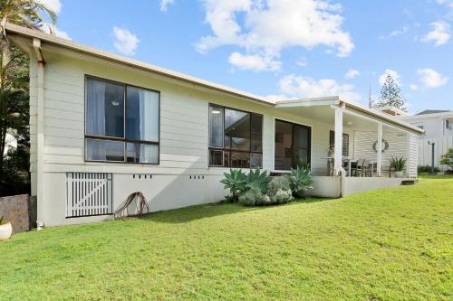 a white house with a lawn in front of it at Baileys Beach House in East Ballina