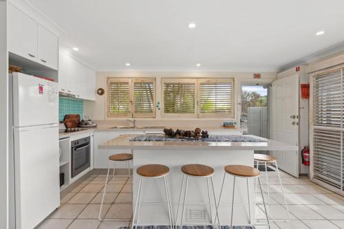 a kitchen with a large island with bar stools at Barefoot in Lennox in Lennox Head