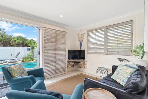 a living room with a couch and a tv at Barefoot in Lennox in Lennox Head