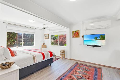 a bedroom with a bed and a tv on the wall at Beach Views in Lennox Head