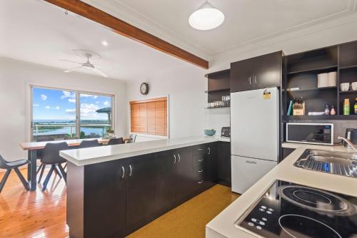 a kitchen with black cabinets and a white refrigerator at Shaws View in East Ballina