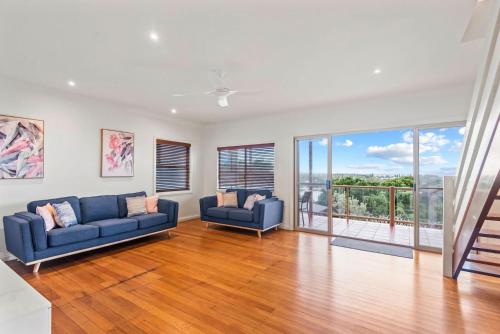 a living room with two blue couches and a balcony at Shaws View in East Ballina