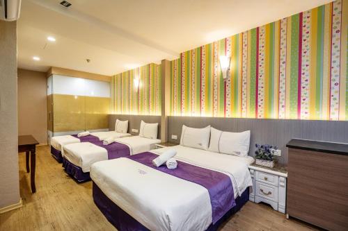 a hotel room with three beds and a television at Lavender Inn Nusa Bestari in Johor Bahru