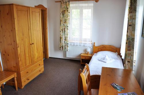a bedroom with a bed and a table and a window at Penzion Diana in Teplice nad Bečvou
