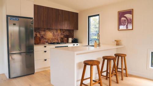 a kitchen with a refrigerator and stools in it at Blue Ash Studio in Lennox Head