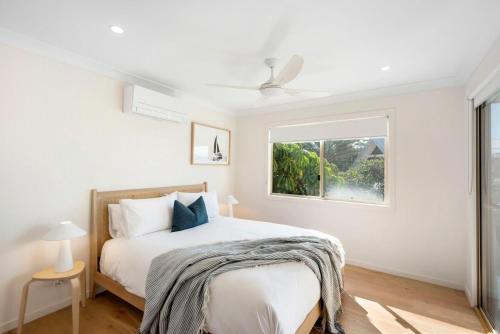 a white bedroom with a bed and a window at Bombora in Lennox Head