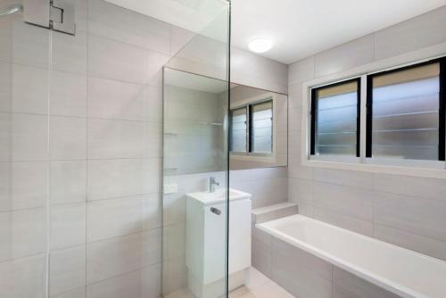 a white bathroom with a tub and a glass shower at Bombora in Lennox Head