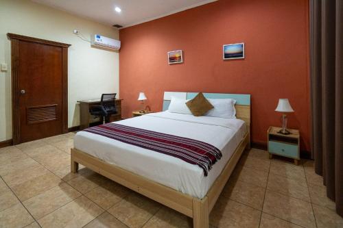 a bedroom with a large bed with a red wall at Sunset INN by Pro-Ema in Dili