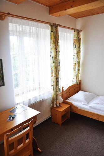 a bedroom with a bed and a desk and a window at Penzion Diana in Teplice nad Bečvou