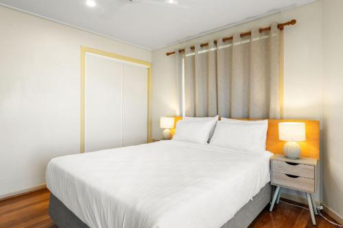 a bedroom with a large white bed and two lamps at Haere Mai 2 in East Ballina