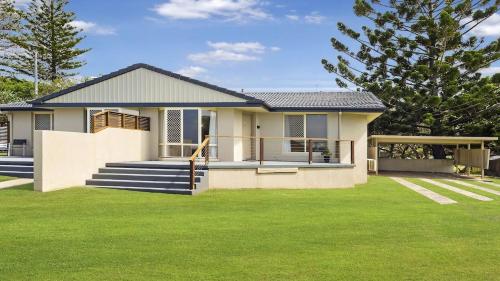 a house with a green lawn in front of it at Haere Mai 2 in East Ballina