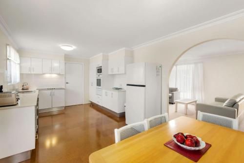 a kitchen and a table with a bowl of fruit on it at Hereford Court East Ballina in East Ballina