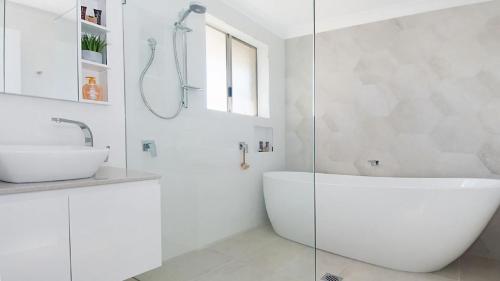 a white bathroom with a tub and a sink at Kay s Hideaway in Lennox Head