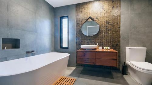 a bathroom with a tub and a sink and a mirror at KK s in Lennox Head in Lennox Head