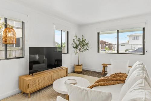 a white living room with a couch and a table at Lennox Beach Shack in Lennox Head