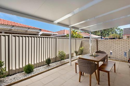 a patio with a table and chairs and a fence at Kenway Lodge in Ballina