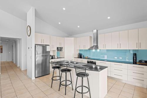 a kitchen with white cabinets and bar stools at Oceanic 3 in East Ballina