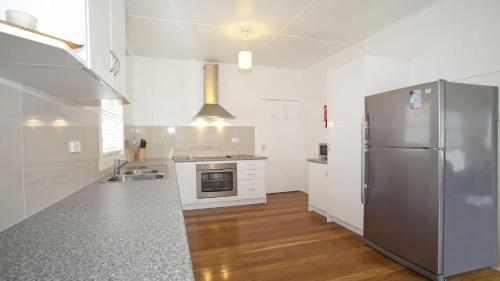 a kitchen with a stainless steel refrigerator and wooden floors at My Blue Heaven Dog Friendly in Lennox Head