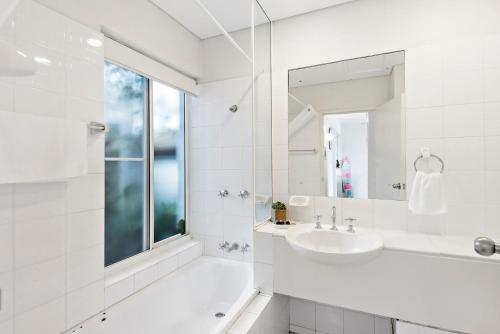 a white bathroom with a sink and a mirror at Quarterdeck 18 in Lennox Head