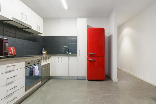 a red refrigerator in a kitchen with white cabinets at Spacious Studio in a Prime Braddon Location - Hosted by Canstay in Braddon