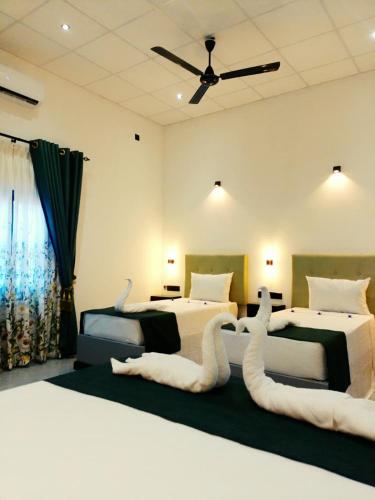 a bedroom with two beds with white cats on them at Vimanra Udawalawa in Udawalawe