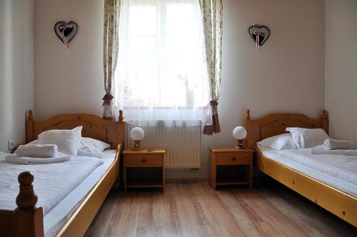 two twin beds in a room with a window at Penzion Diana in Teplice nad Bečvou