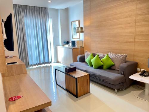 a living room with a couch with green pillows at Korapura Resort in Nakhon Ratchasima
