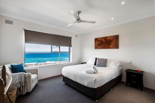 a bedroom with a bed and a chair and a window at Surf Sea and Sand in East Ballina