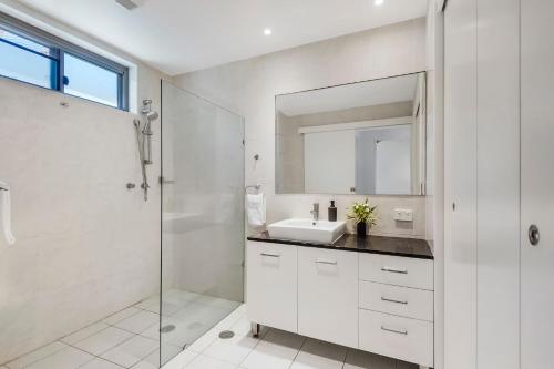a white bathroom with a sink and a shower at Surf Sea and Sand in East Ballina