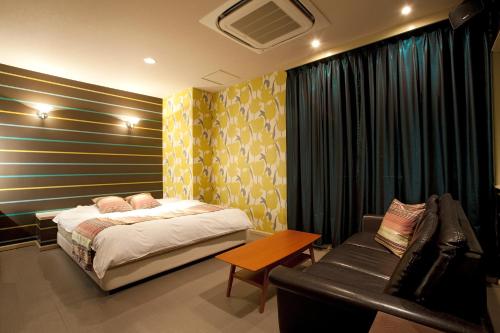 a bedroom with a bed and a couch at ホテルラフィネ in Toyonaka