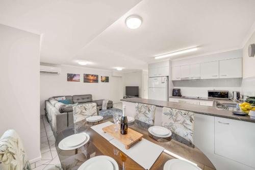 a kitchen and living room with white cabinets and a table at Sunshine Hideaway - Easy Beachside Living in Mooloolaba