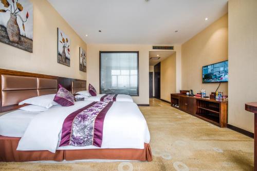 ein großes Schlafzimmer mit einem großen Bett und einem Fernseher in der Unterkunft Minghua Hotel in Wen-su-lao-ch'eng