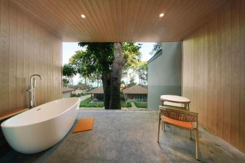 a bathroom with a tub and a chair and a tree at Samed Amoris Resort & Pool Villas in Ko Samed